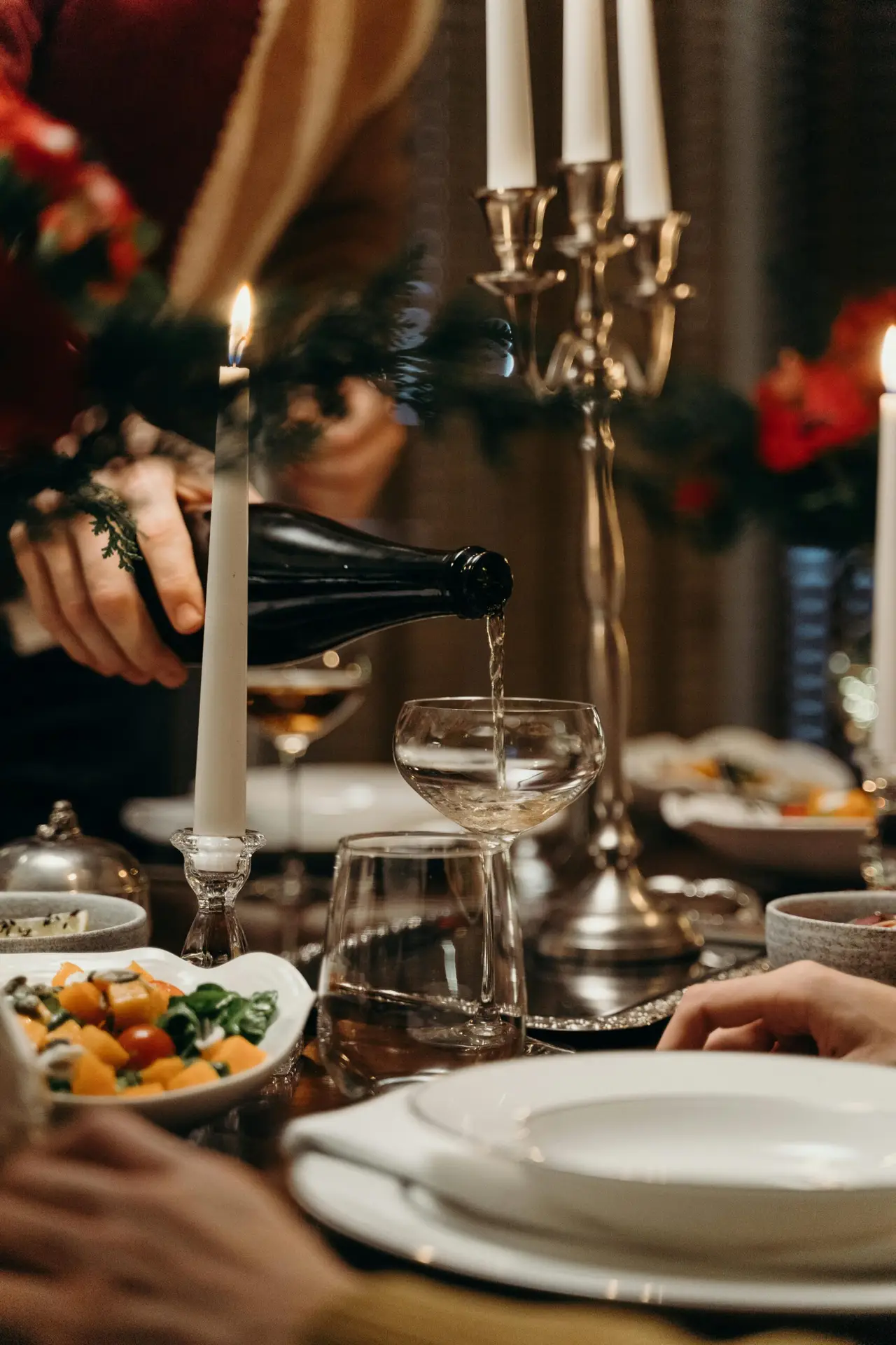 Close-up of champagne being poured into a coupe glass at an elegant dinner setting.