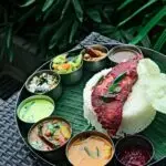 Delicious Kerala rice meal with assorted curries and fried fish served on a banana leaf.