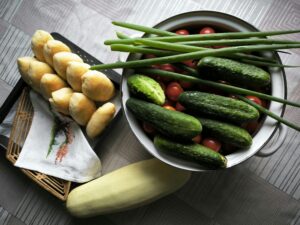 Fresh cucumbers, tomatoes, and homemade buns artfully arranged on a table for a rustic dining experience.