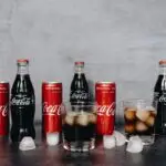 Chilled Coca Cola bottles and cans surrounded by ice cubes, offering a refreshing beverage choice.