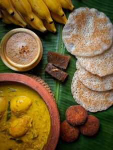 Top view of Indian cuisine featuring dosa, curry, bananas, and coffee on a banana leaf.