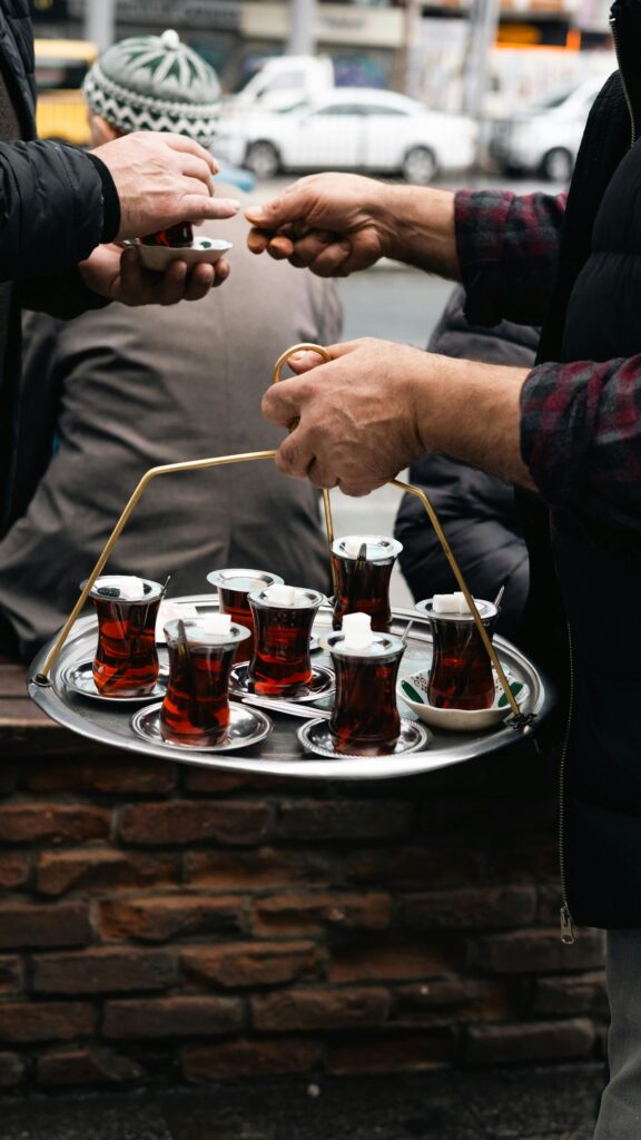 Turkish tea served outdoors on a tray during a street transaction in a bustling environment.